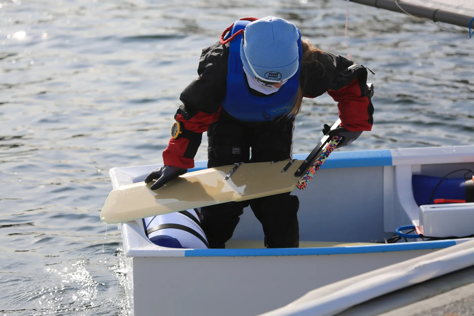 A young sailor fitting the rudder to an Optimist