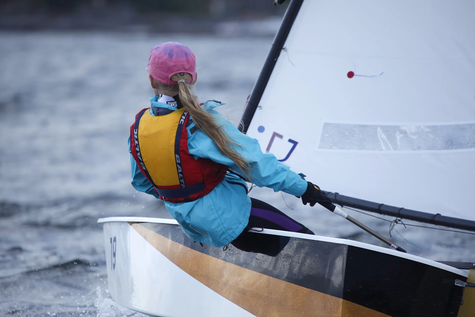 A young sailor hiking out in an Optimist